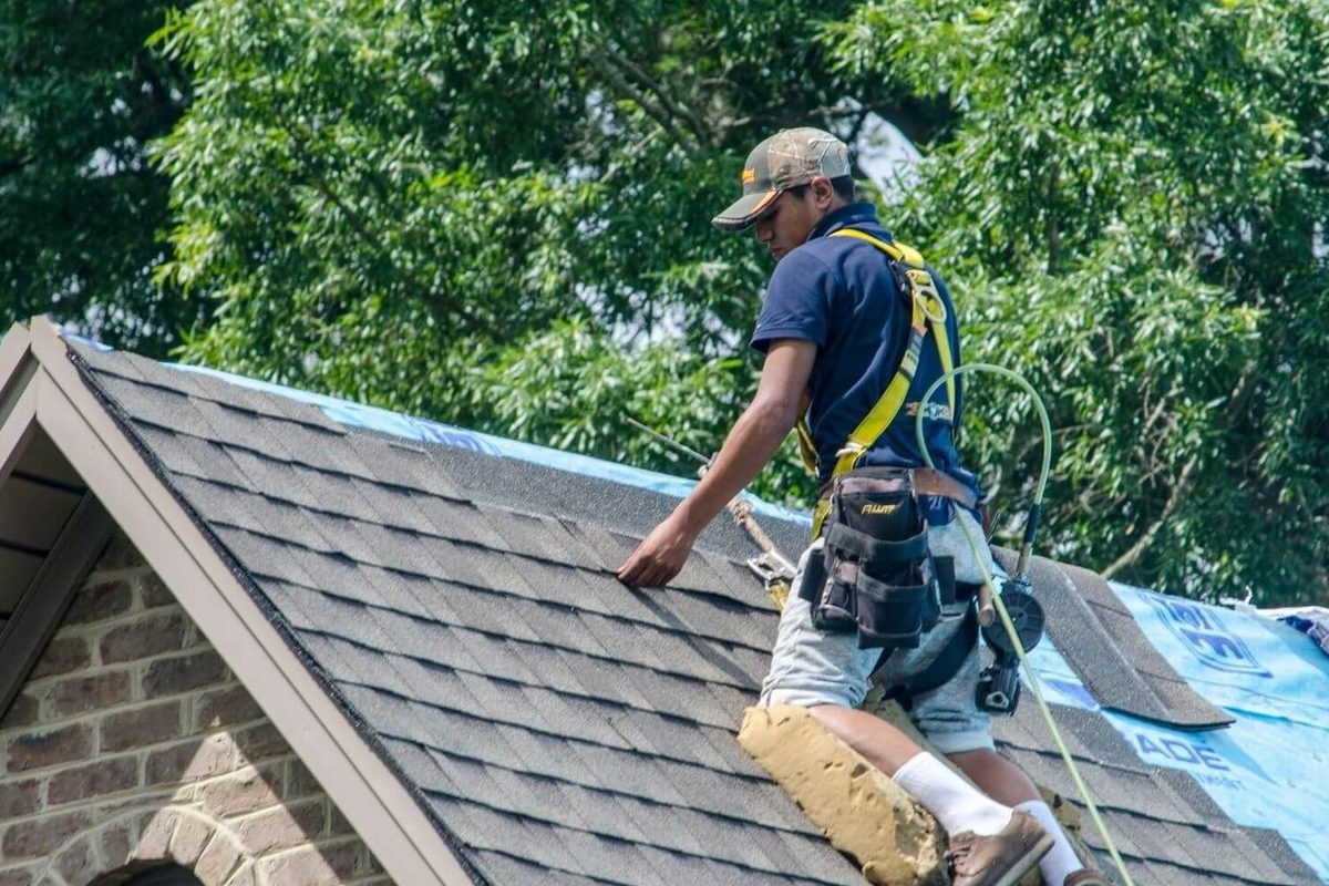 Roof repair technician on an Indianapolis home securing shingles on a steep slope